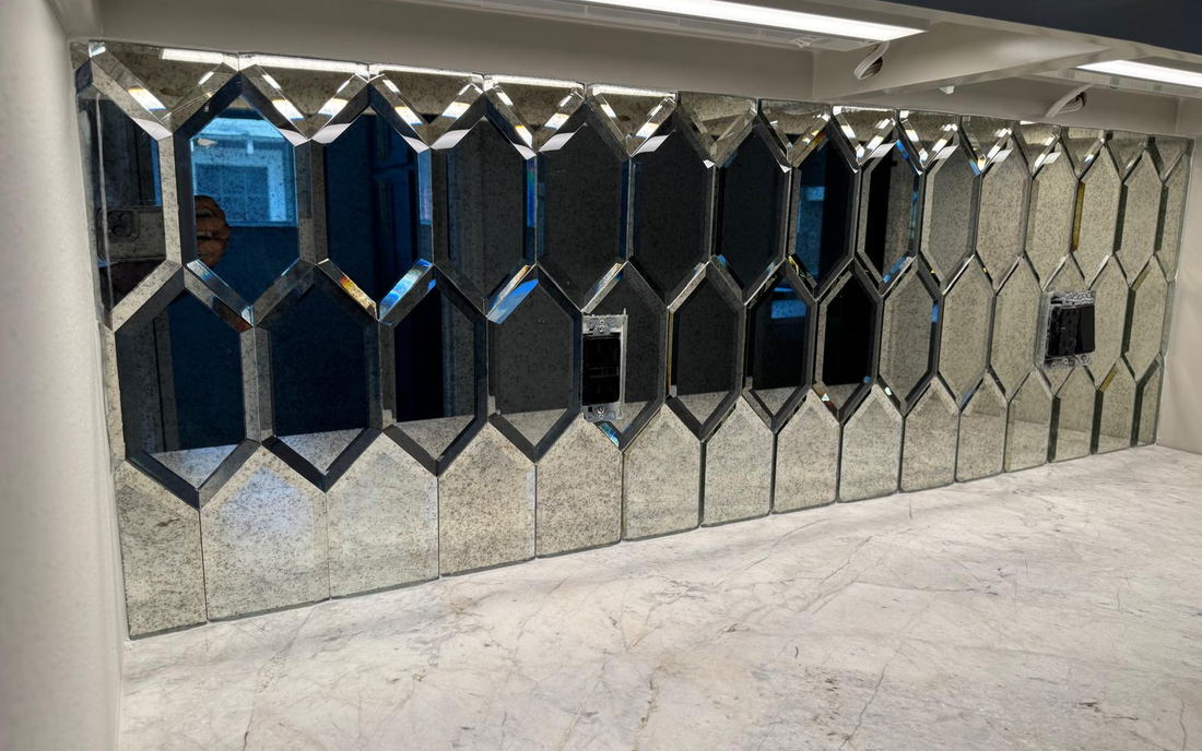 Antique mirrored hexagon backsplash with beveled edges seen at an angle under cabinet lighting