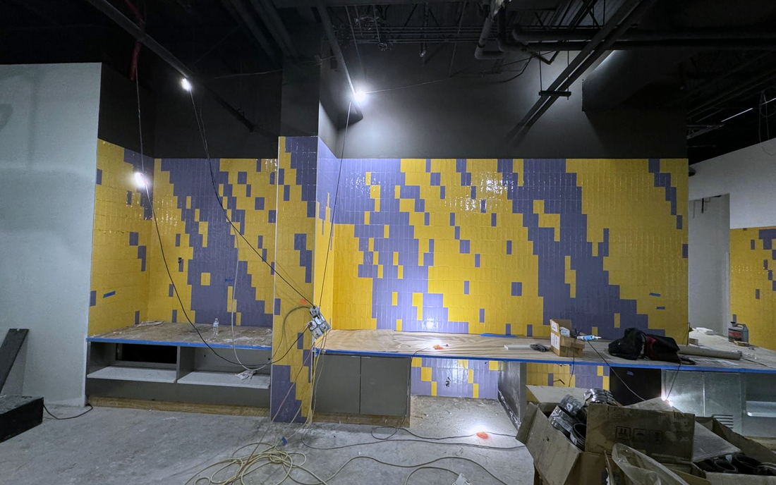 Commercial feature wall in yellow and purple tile forming a pixelated pattern above a service counter