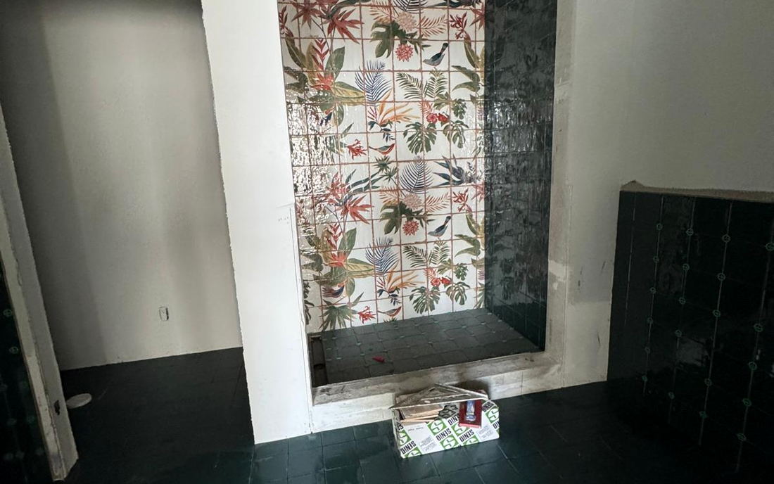 Bathroom stripped back to the original floral wall tile and dark floor tile before new work begins