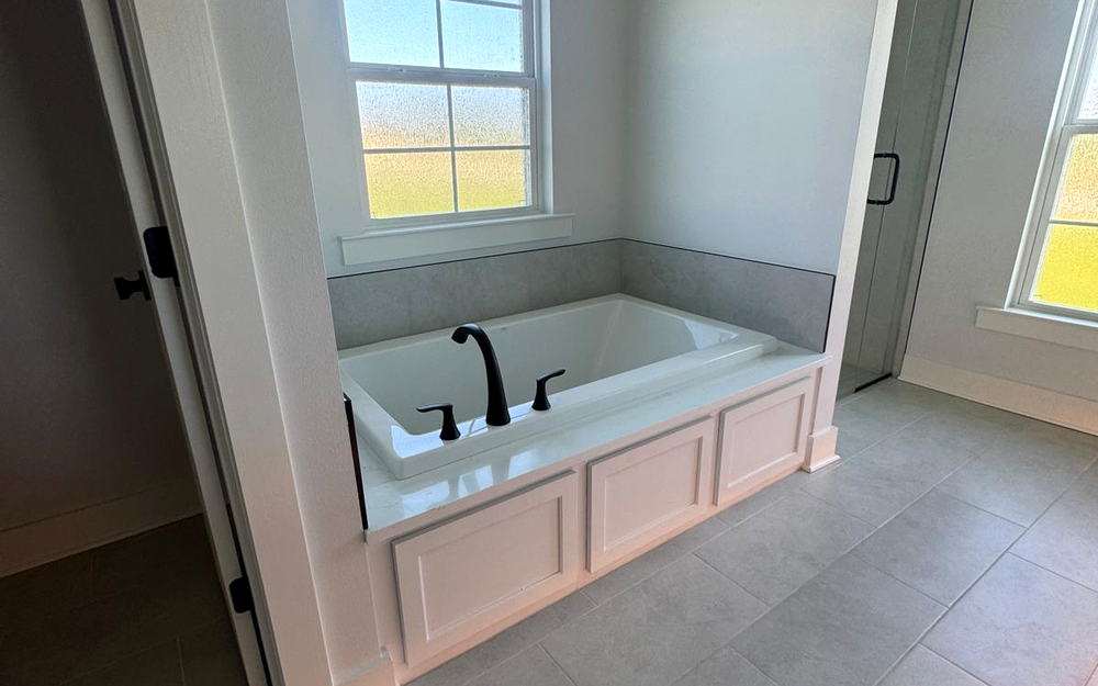 Garden tub set into a tiled deck with a porcelain tile floor running through the bathroom