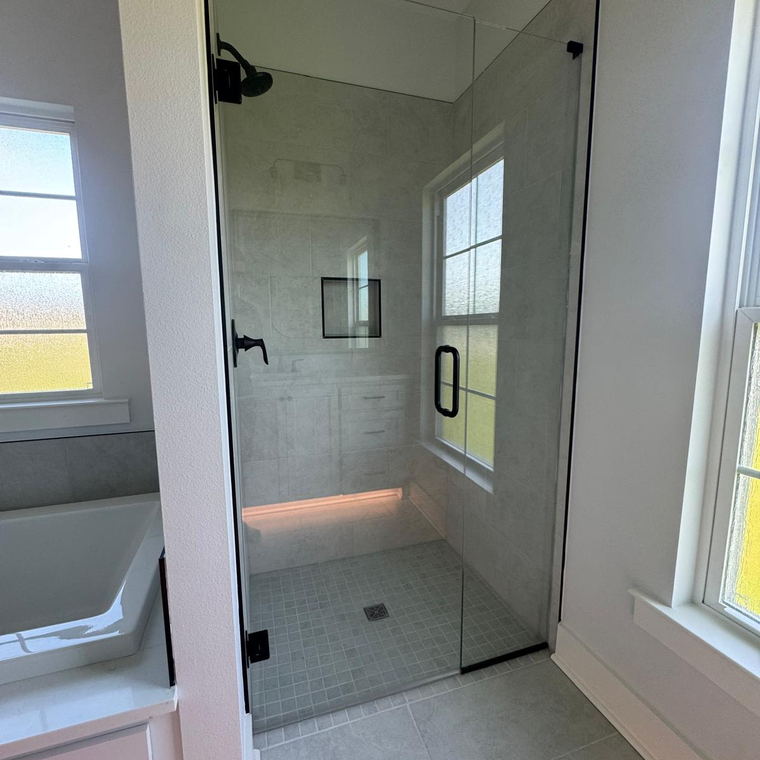Corner shower in grey porcelain with a recessed niche, small square mosaic pan and a frameless glass door