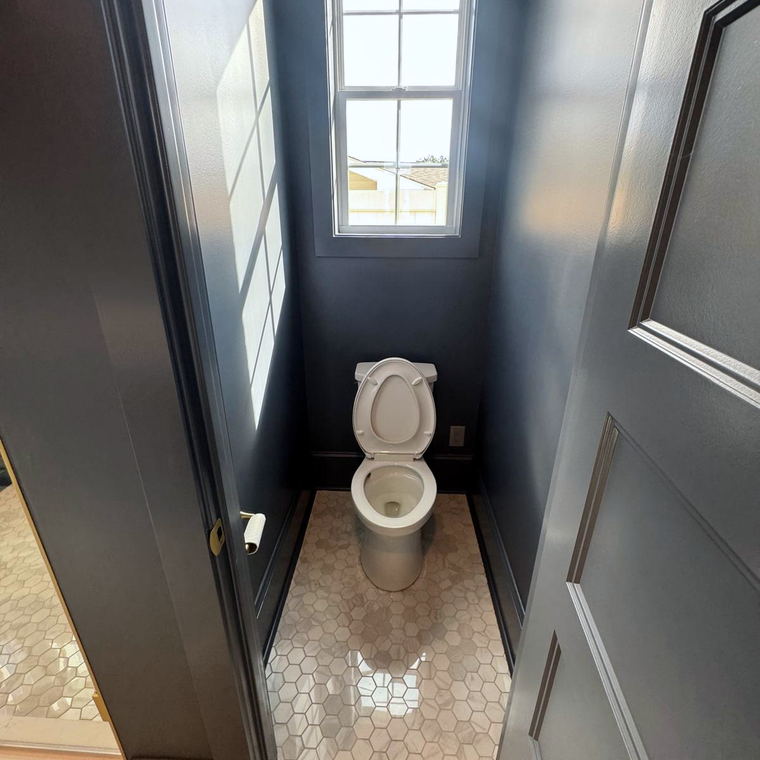 Narrow powder room with navy walls and trim over a white marble hexagon mosaic floor