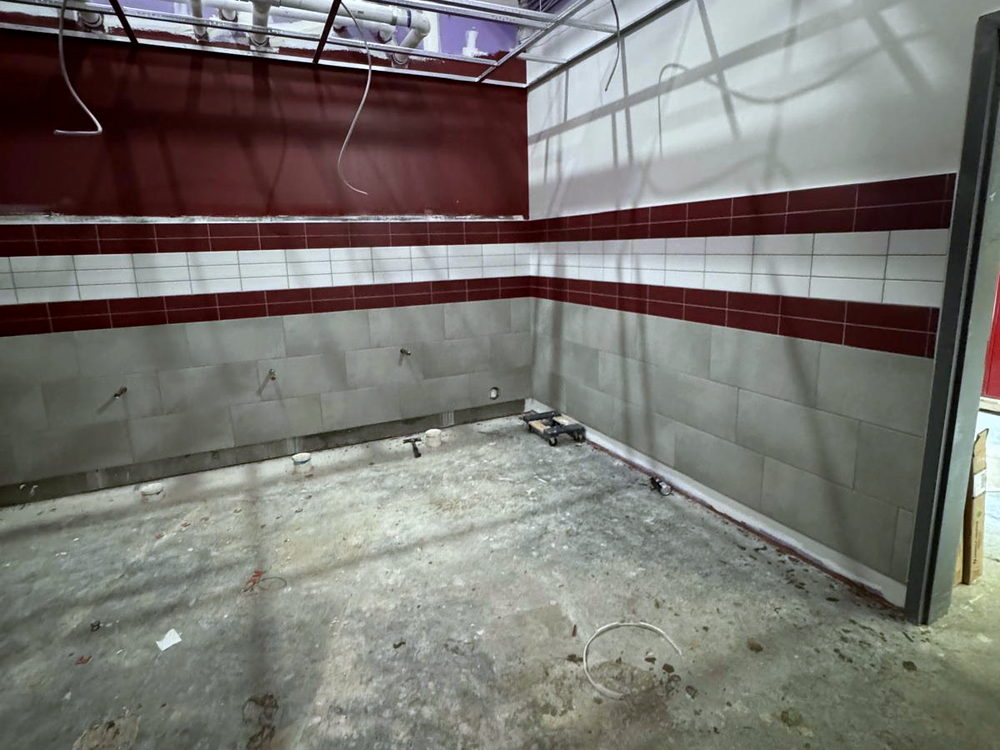 Commercial interior still under construction, with a tiled wainscot finished and the concrete slab left bare