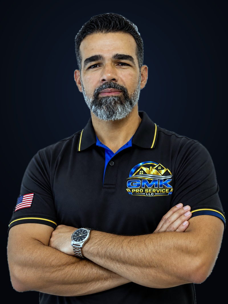 Gleison, founder of GMK Pro Service LLC, arms crossed, wearing the company polo shirt with the GMK logo and a US flag patch on the sleeve