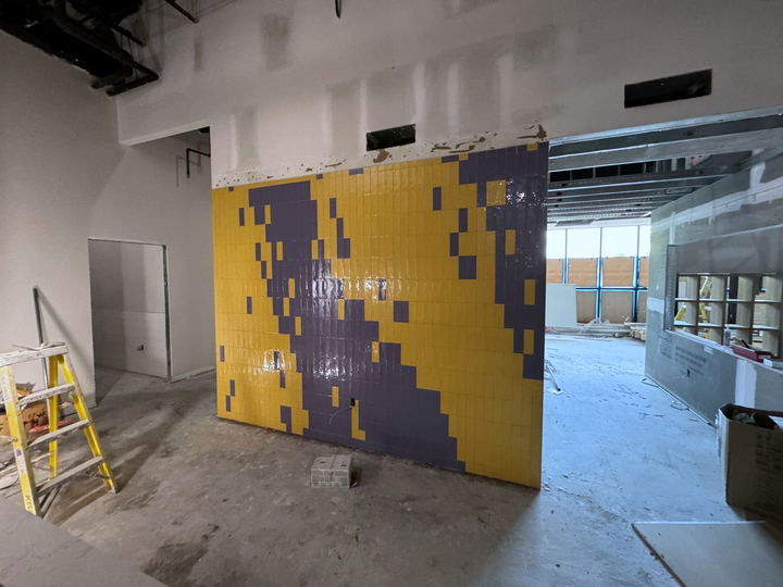 Freestanding yellow and purple tile feature wall in a commercial interior still under construction
