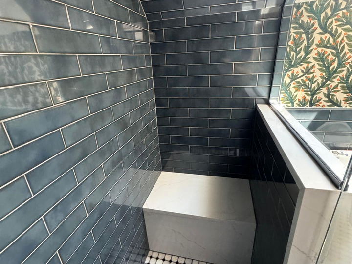 Dark blue subway shower with a white quartz bench and a marble octagon mosaic pan under a sloped ceiling