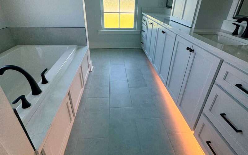 Master bathroom with a garden tub, tiled floor and a long white vanity with under-cabinet lighting